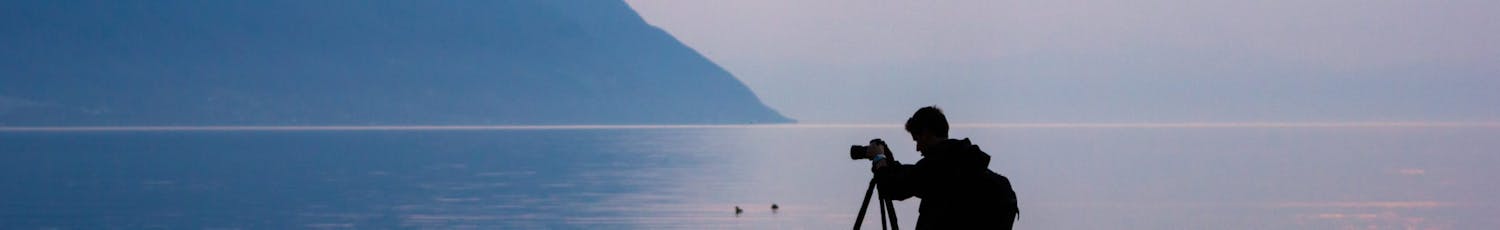 Man fotograferar landskap vid vattnet.